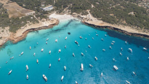 many boats over turquoise sea and small cliff. Cala Saona in Formentera island.